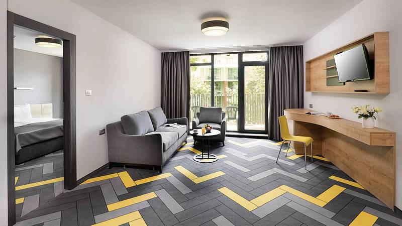 Innenansicht des HVD Club Bor Hotels mit Wohnzimmer, Schlafbereich und modernem Design.
