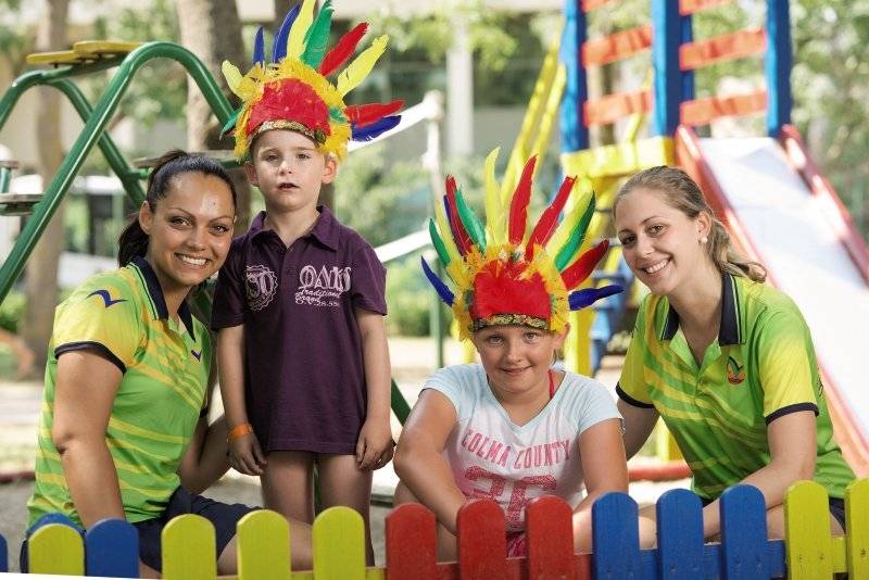 Familie im HVD Club Bor Freizeitpark, Kinder mit Federkopfbedeckungen und Erwachsenen.