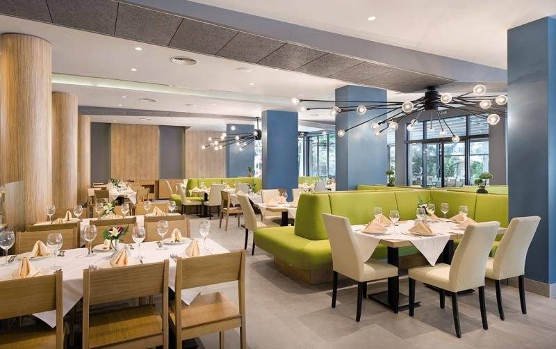 Innenansicht des Restaurants im HVD Club Bor mit grünen Sofas und gedeckten Tischen.