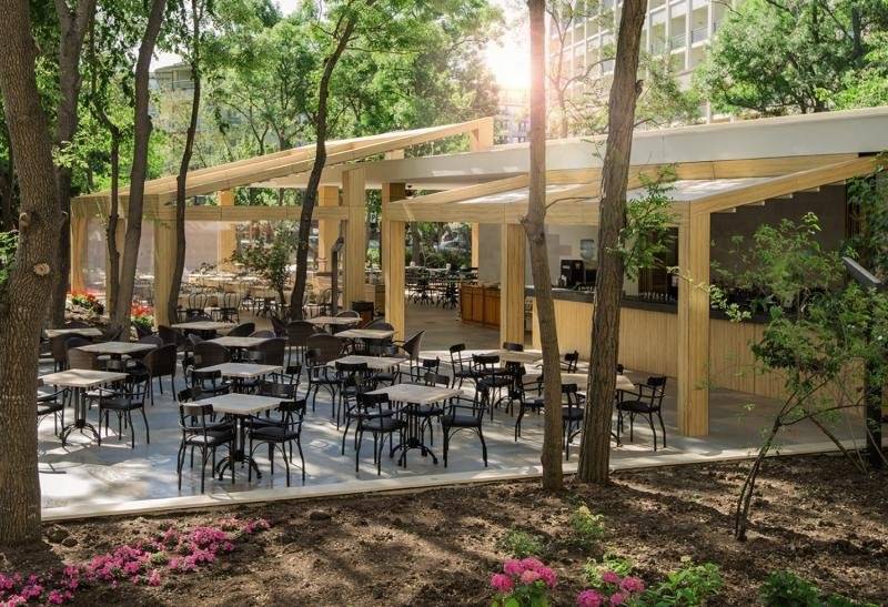 Terrasse des HVD Club Bor Hotels mit Tischen, Stühlen und Bäumen.
