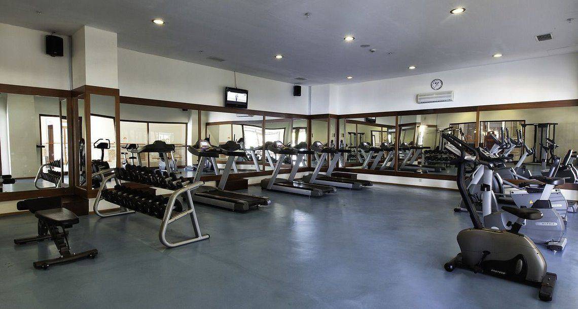 Fitnesscenter im Adalya ArtSide Hotel mit verschiedenen Geräten und Spiegeln.