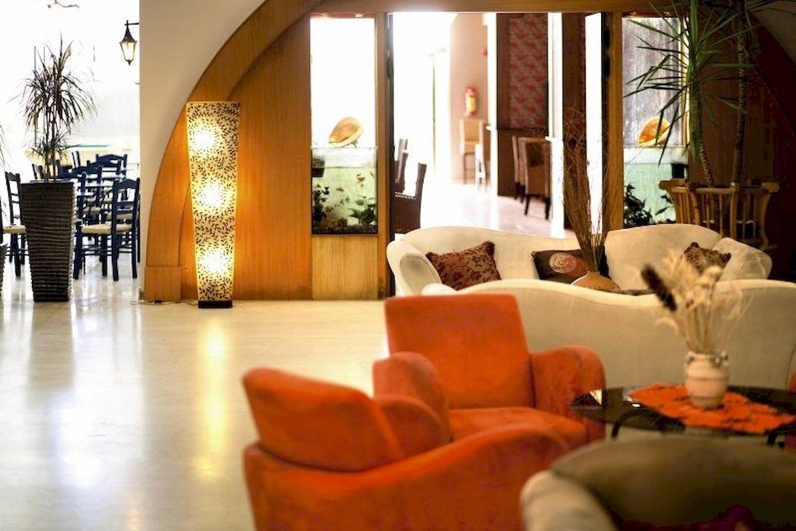 Hotellobby des Irene Palace Beach Resort mit orangefarbenen Sesseln, weißen Sofas und einem Aquarium.