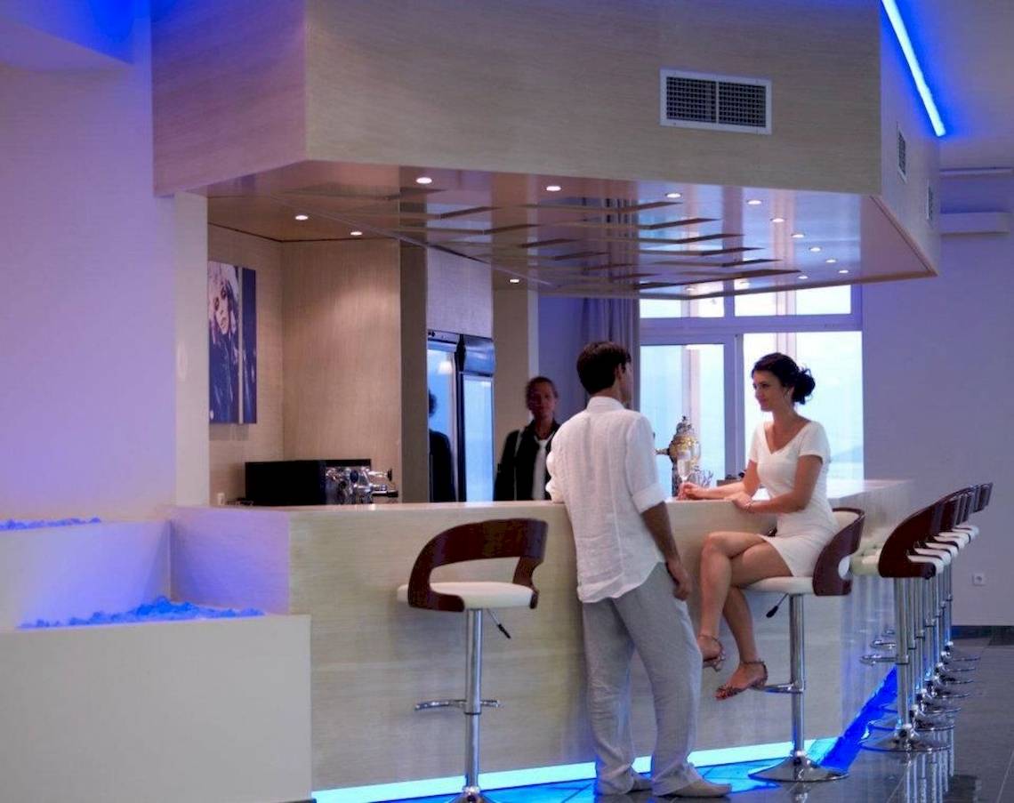 Ein Paar steht an der Bar im Proteas Blu Resort, während zwei Personen im Hintergrund stehen.