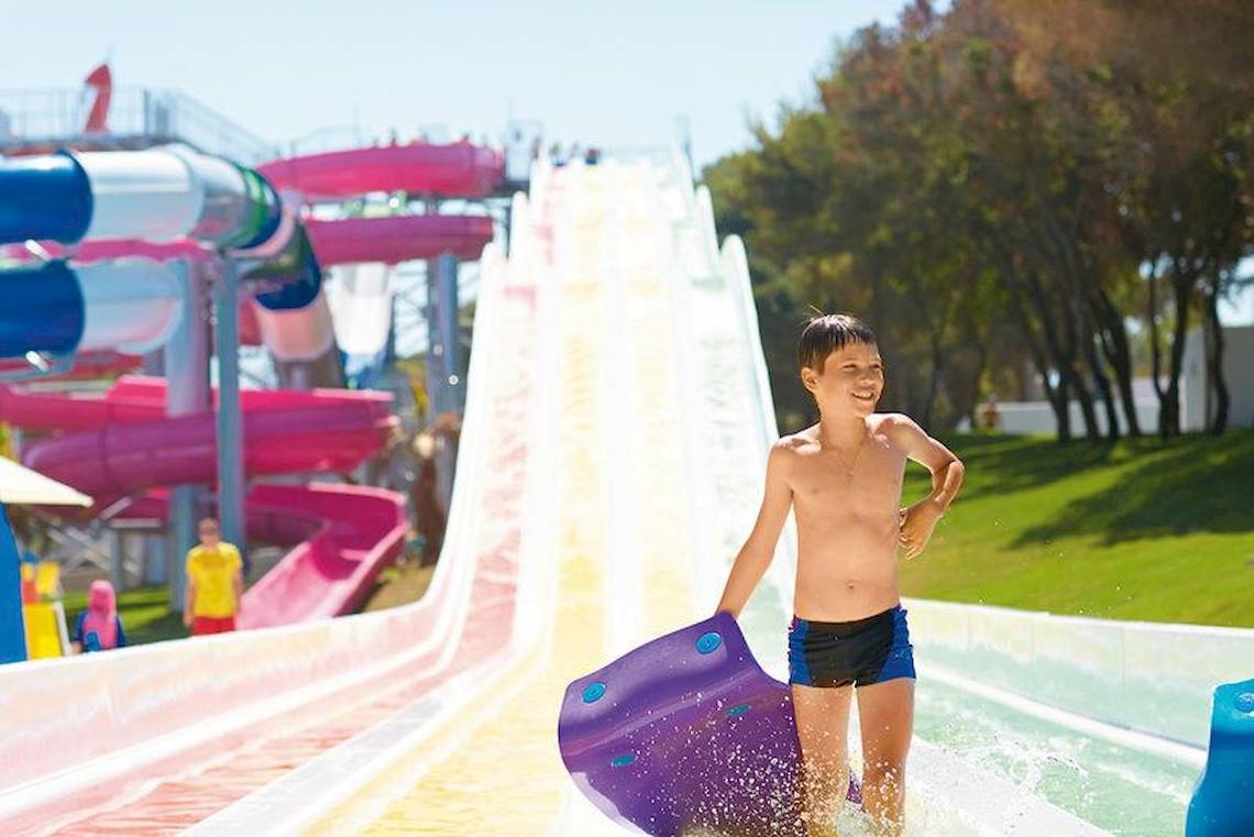 Junge rutscht auf einer bunten Wasserrutsche im Grecotel Olympia Oasis Aqua Park.