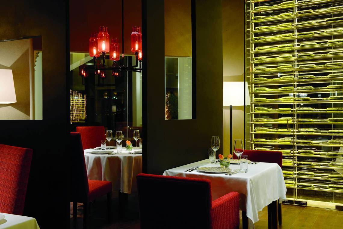 Innenansicht des Ritz Carlton Abu Dhabi Grand Canal Restaurants mit gedeckten Tischen und roten Stühlen.