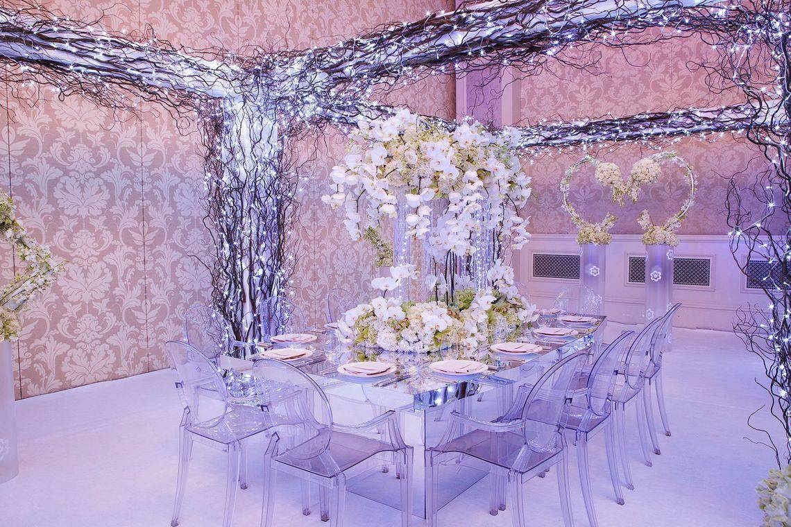 Der Bankettsaal im Ritz Carlton Abu Dhabi Grand Canal mit Glastisch, klaren Stühlen und Blumendekoration.