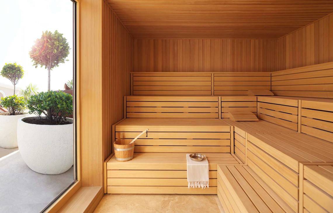 Innenansicht einer Sauna im Ritz Carlton Abu Dhabi mit Holzbänken, einem Eimer und einem Handtuch.