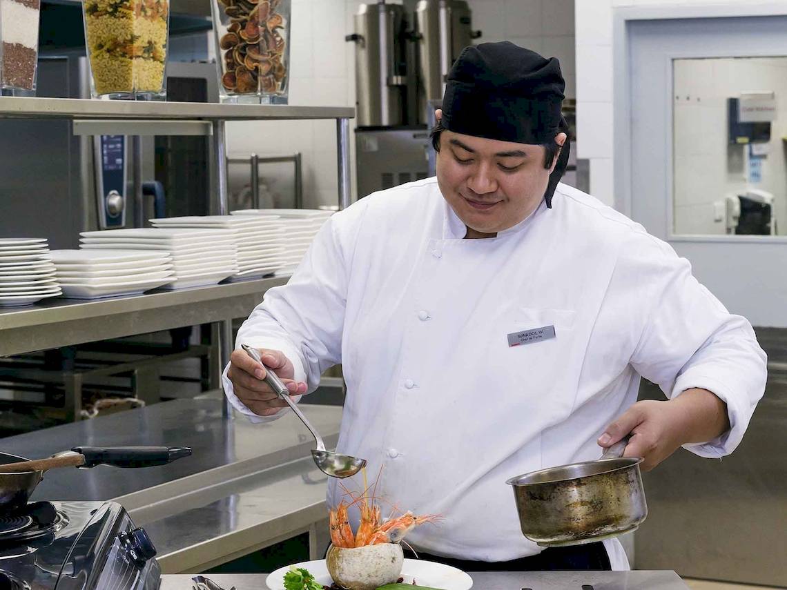 Koch im Mercure Bangkok Siam präsentiert ein Gericht in der Küche
