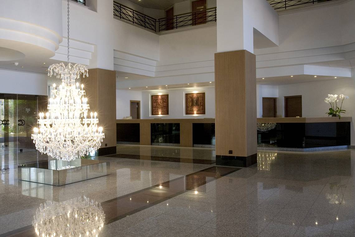 Empfangsbereich des Venus Beach Hotels mit großem Kristallkronleuchter und modernem Design.