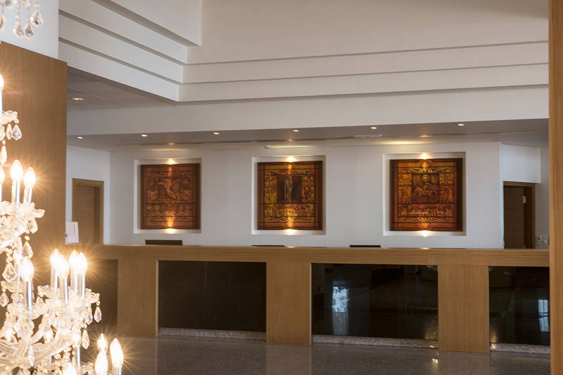 Empfangstresen im Venus Beach Hotel mit drei kunstvollen Wandbildern und einem Kristallkronleuchter.