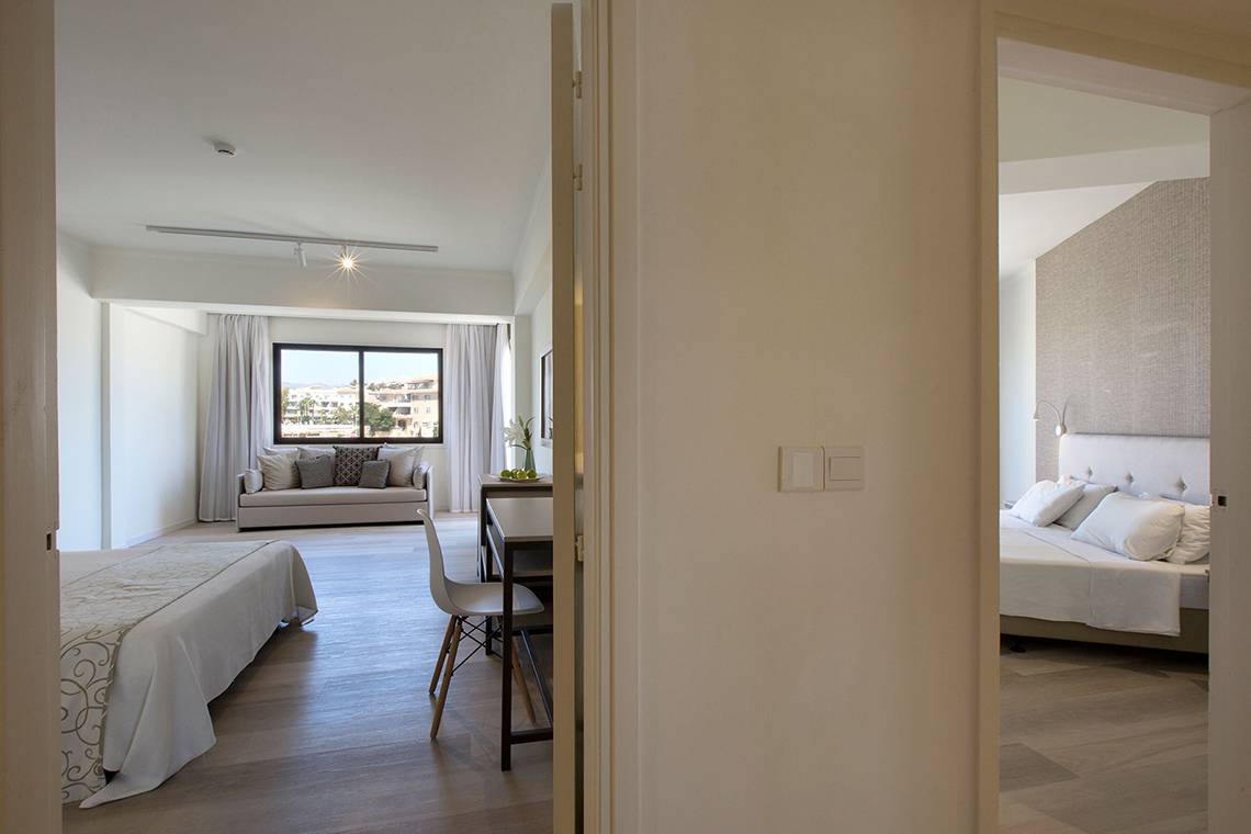 Innenansicht eines Zimmers im Venus Beach Hotel mit einem Bett, einem Schreibtisch, einem Stuhl und einer Couch.