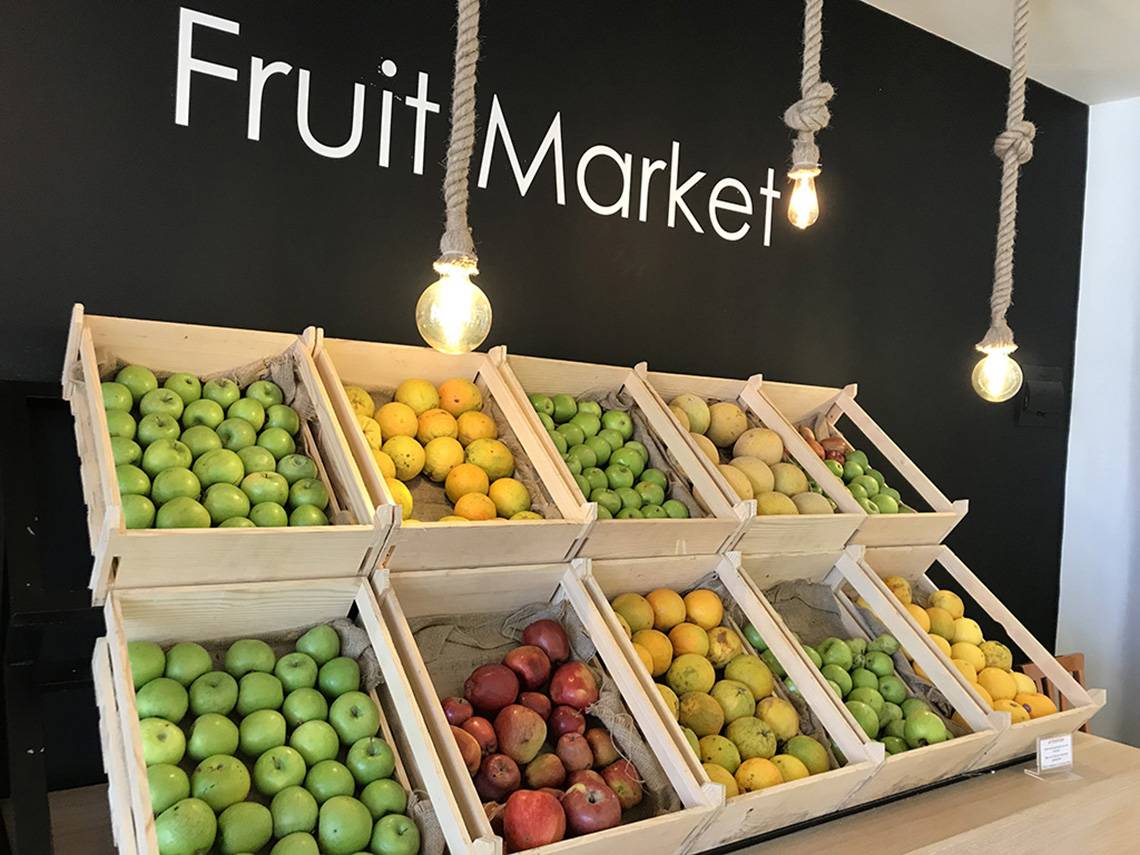 Eine Tafel mit verschiedenen Obstsorten wie Äpfeln, Orangen und Mandarinen in Kisten.