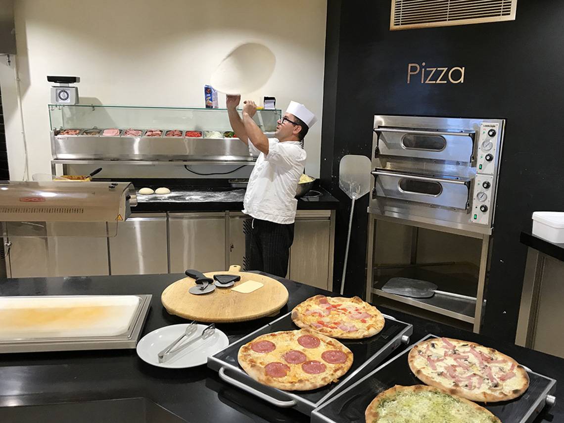 Koch in der Küche des Aphrodite Beach Club, der eine Pizza mit den Händen in der Luft formt.
