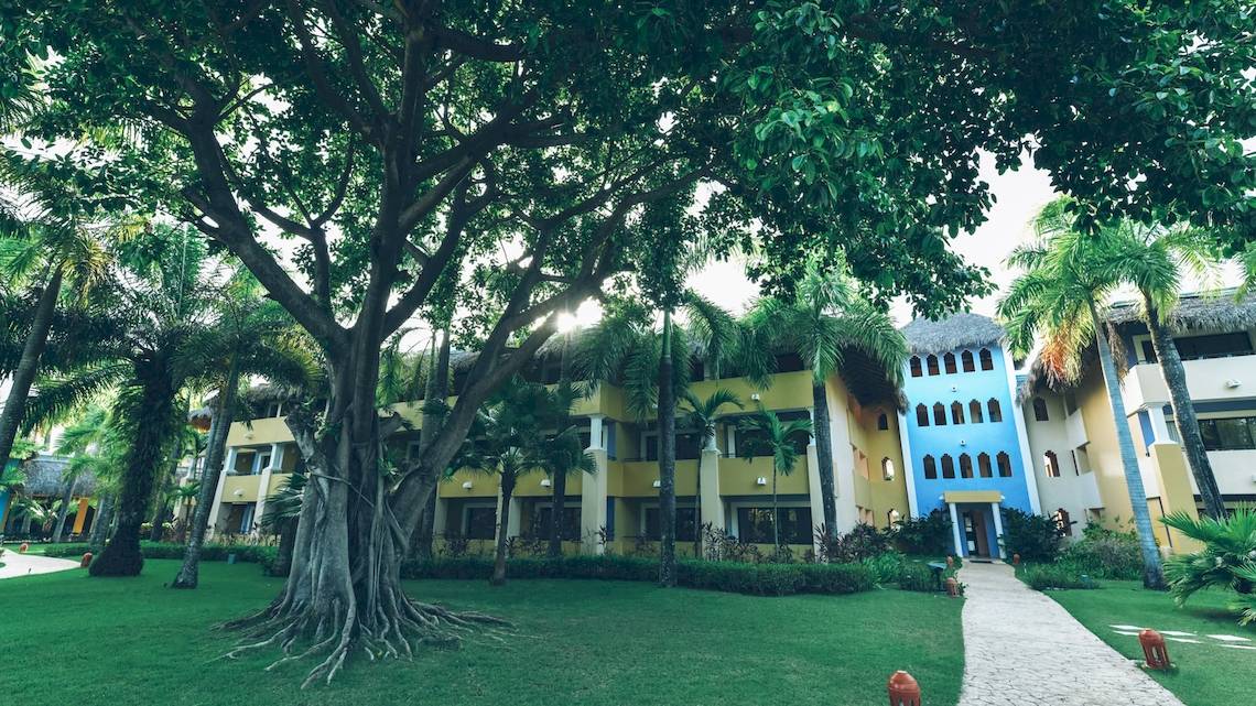 Außenansicht des Iberostar Costa Dorada Hotels mit Gebäuden, Bäumen und Rasen.