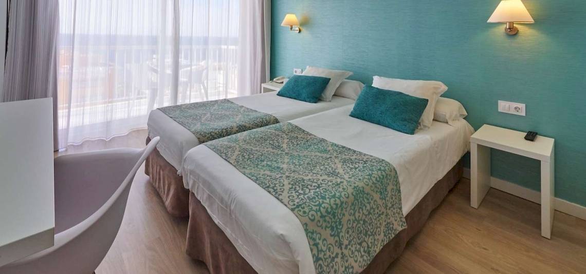 Doppelzimmer mit Meerblick im BQ Apolo Hotel, mit zwei Betten, blauen Kissen und einem Blick auf das Meer.