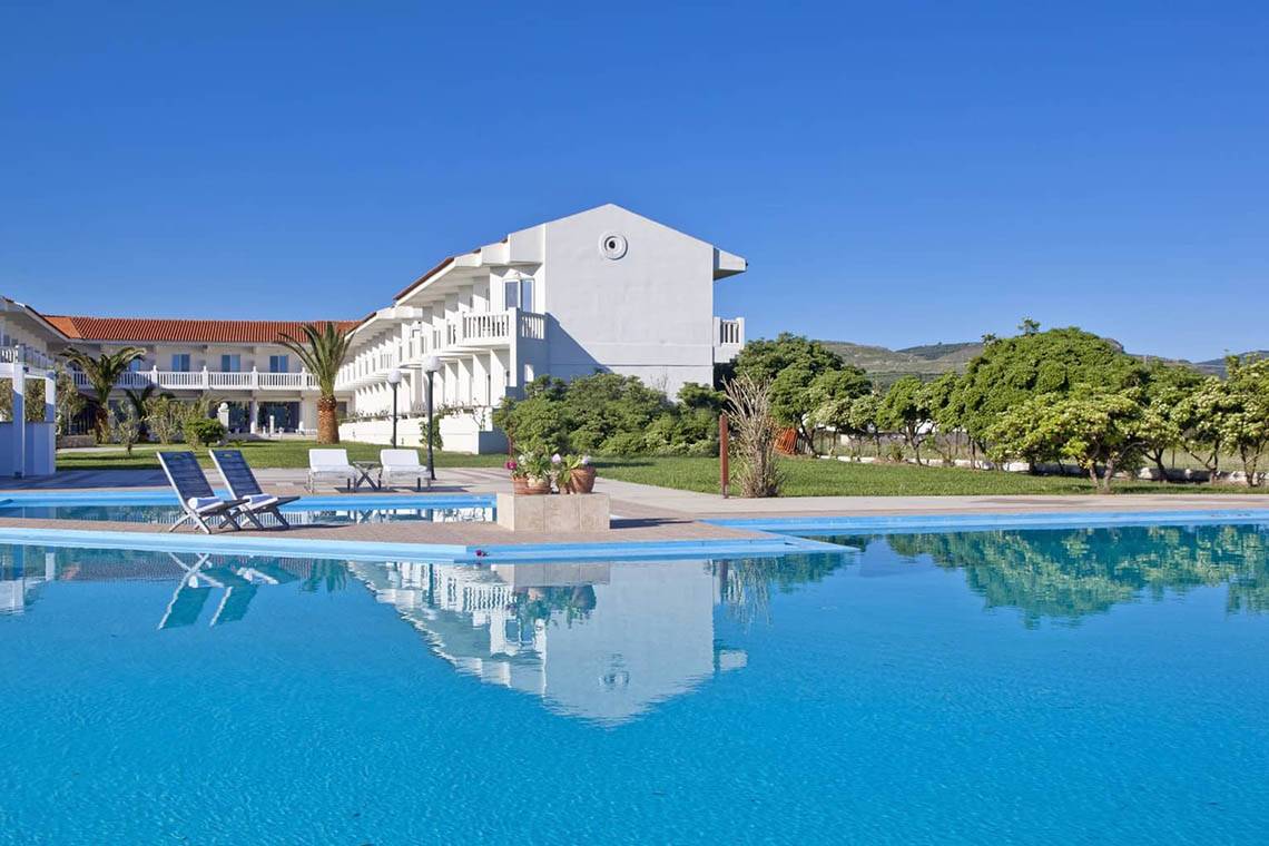 Außenbereich des Mrs Chryssana Beach Hotels mit Pool und Liegestühlen.