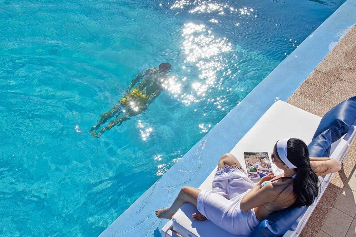 Frau am Rand des Pools von Mrs Chryssana Beach Hotel liest ein Buch