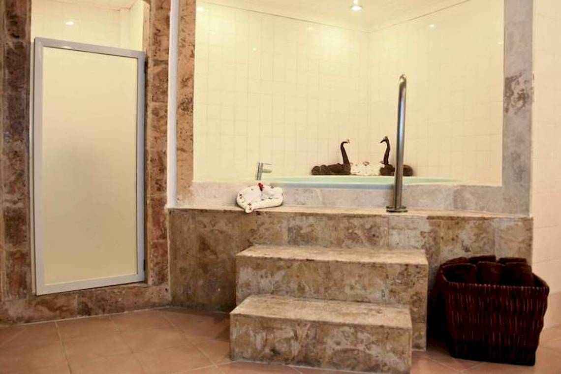 Badezimmer im Dreams Flora Resort & Spa mit Whirlpool und zwei schwarzen Schwanenfiguren.