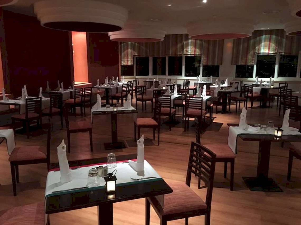 Innenansicht des Restaurants im Golden Tulip Taj Sultan mit gedeckten Tischen und Stühlen.
