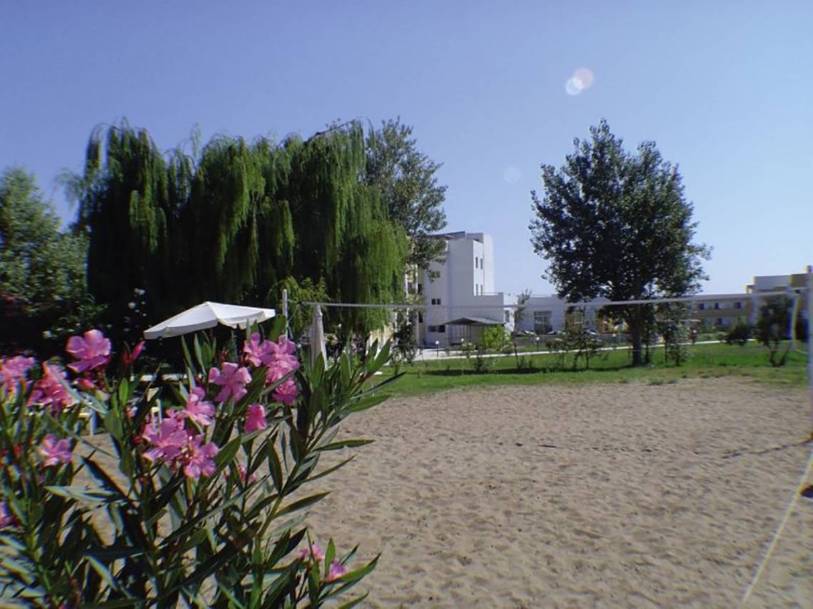 Strand mit Blumen und einem Hotelgebäude im Hintergrund, Pyli Bay Hotel