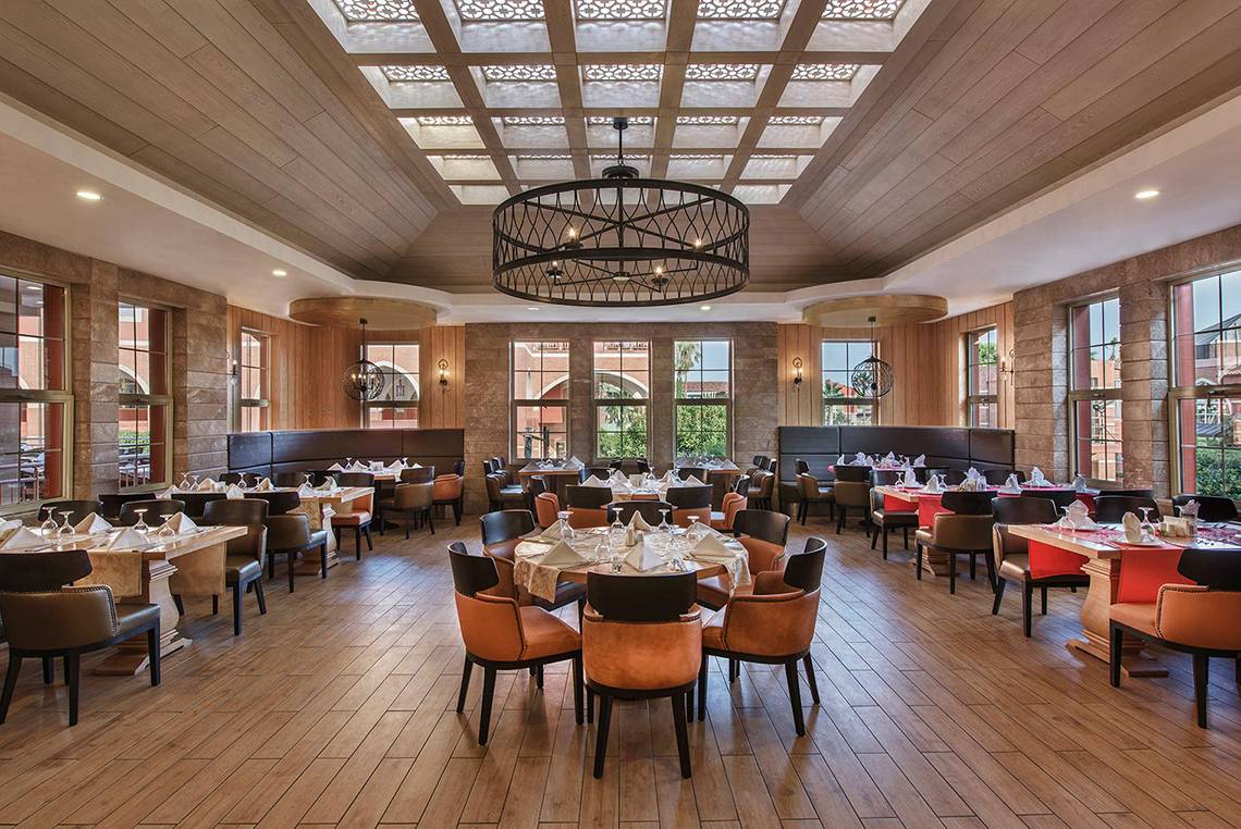 Innenansicht des Restaurants im Megasaray Club Belek mit Holzboden und Tischdekoration.