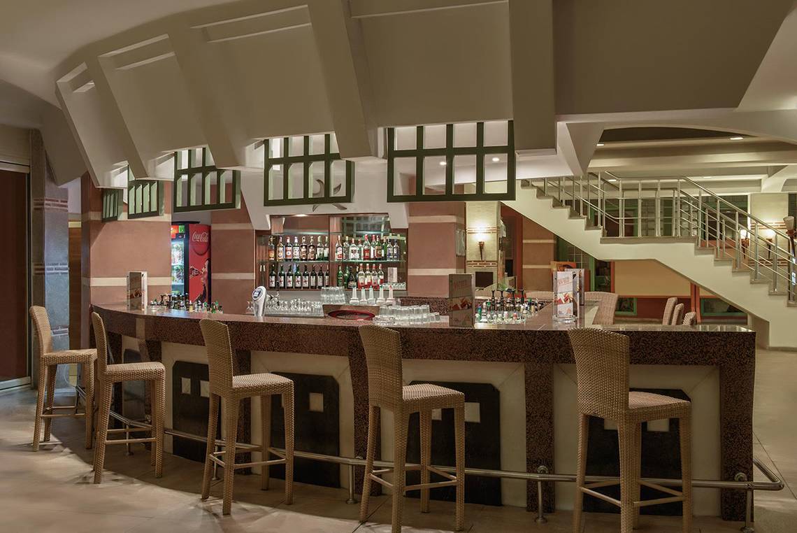 Innenansicht der Bar im Megasaray Club Belek Hotel mit Tresen, Stühlen und Getränken.