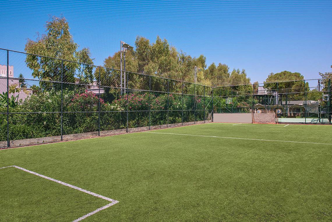 Tennisplatz im Freien am Megasaray Club Belek mit gepflegtem Rasen und umzäuntem Bereich.