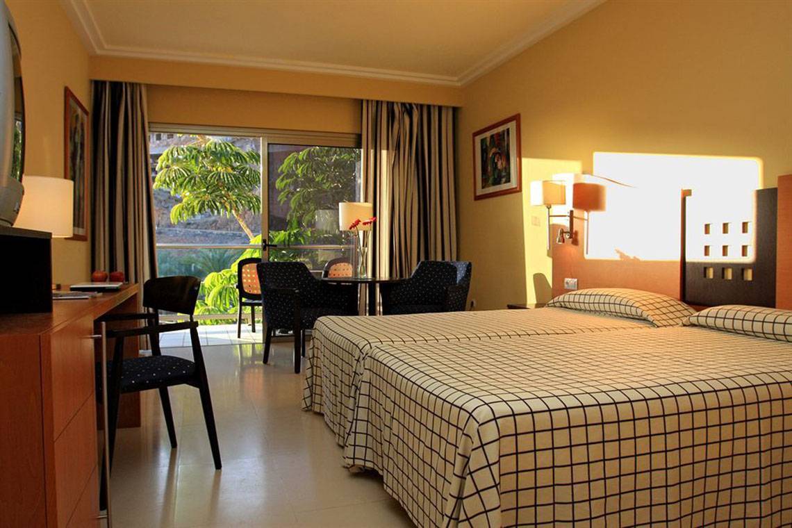 Innenansicht eines Zimmers im LIVVO Costa Taurito Hotel mit zwei Betten, Schreibtisch und Sitzbereich.