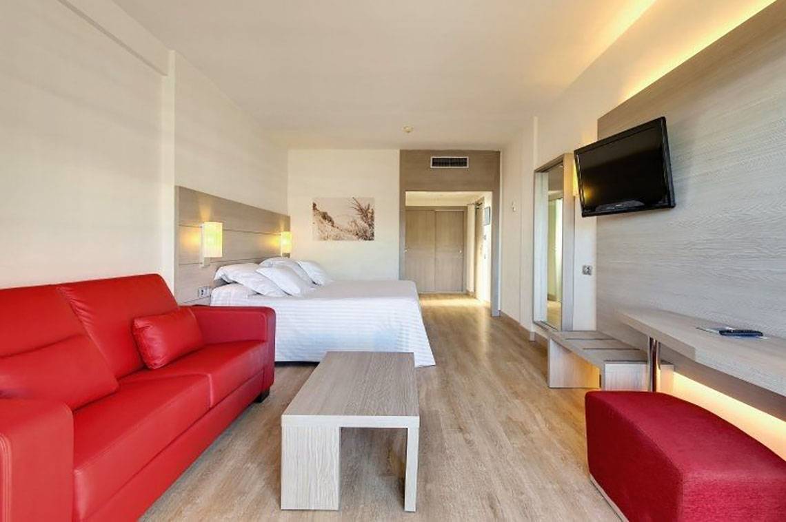 Hotelzimmer im Barcelo Margaritas mit rotem Sofa, Tisch, Bett und Fernseher.