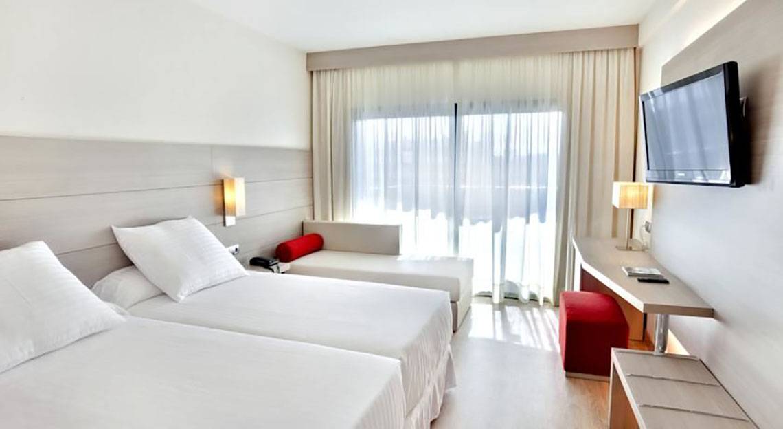 Doppelzimmer im Barcelo Margaritas Hotel mit zwei Betten, einem Sofa, einem Schreibtisch und einem Fernseher.