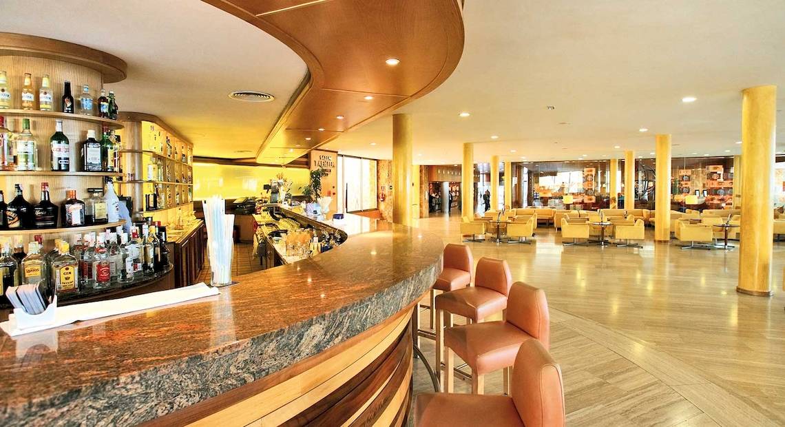 Die Lobbybar des Barcelo Fuerteventura Mar Hotels mit einer großen Auswahl an Getränken und gepolsterten Stühlen.