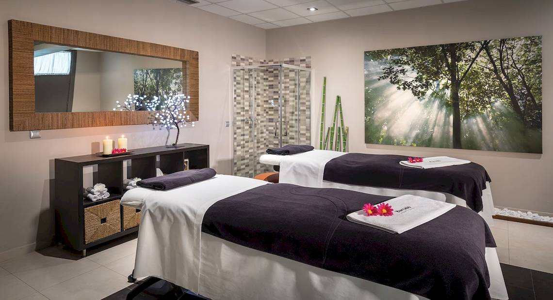 Spa-Behandlungsraum im Barcelo Fuerteventura Mar Hotel mit zwei Behandlungstischen, Kerzen und einem großen Gemälde.