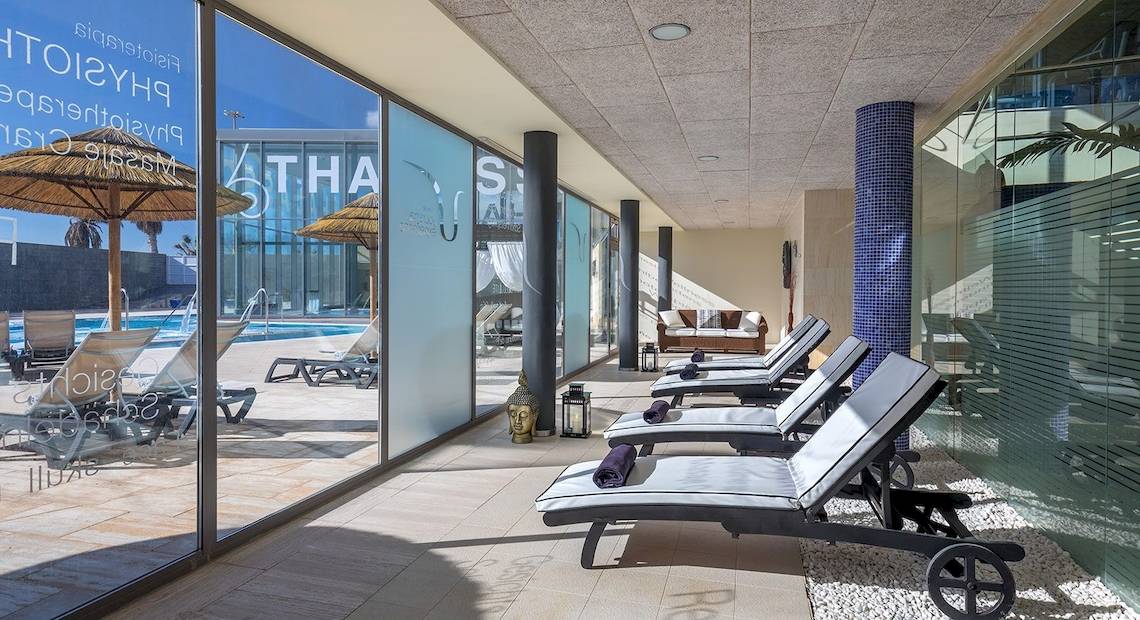 Loungebereich des Barcelo Fuerteventura Mar Hotels mit Sonnenliegen und Glaswänden.