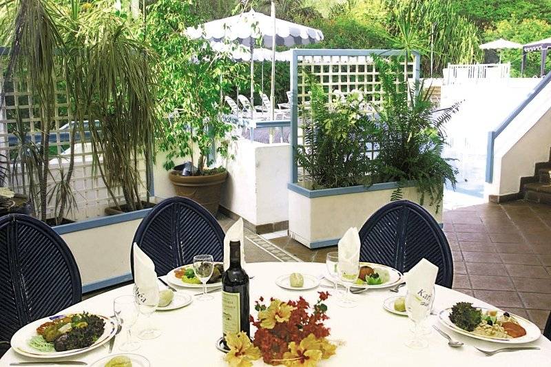 Essen im Garten des Karibea Sainte Luce Hotels mit Tisch, Tellern und Pflanzen.