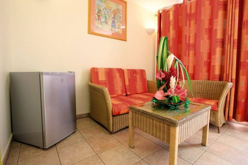 Zimmer im Karibea Sainte Luce Hotel mit einem Sofa, einem Tisch und einem Kühlschrank.