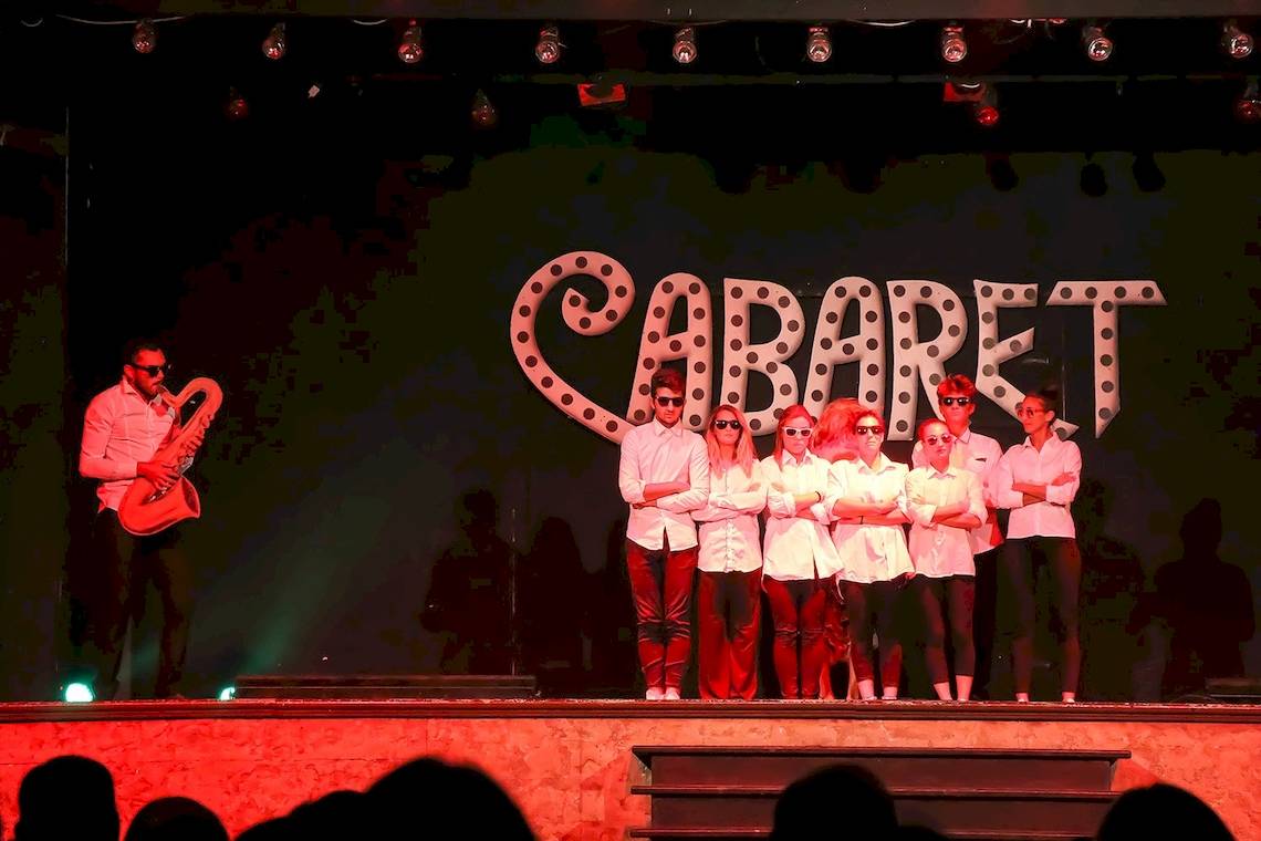 Aufführung eines Cabarets mit einem Musiker und Schauspielern auf der Bühne.