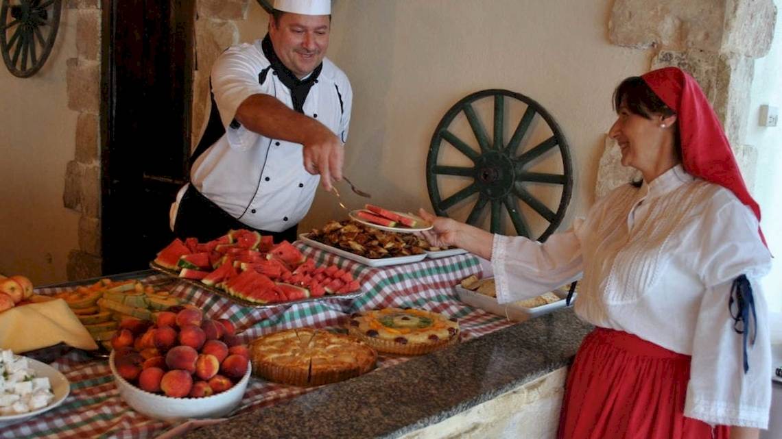 Ein Koch im Seashells Resort serviert einer Frau ein Buffet mit Wassermelonen, Obst und Kuchen.
