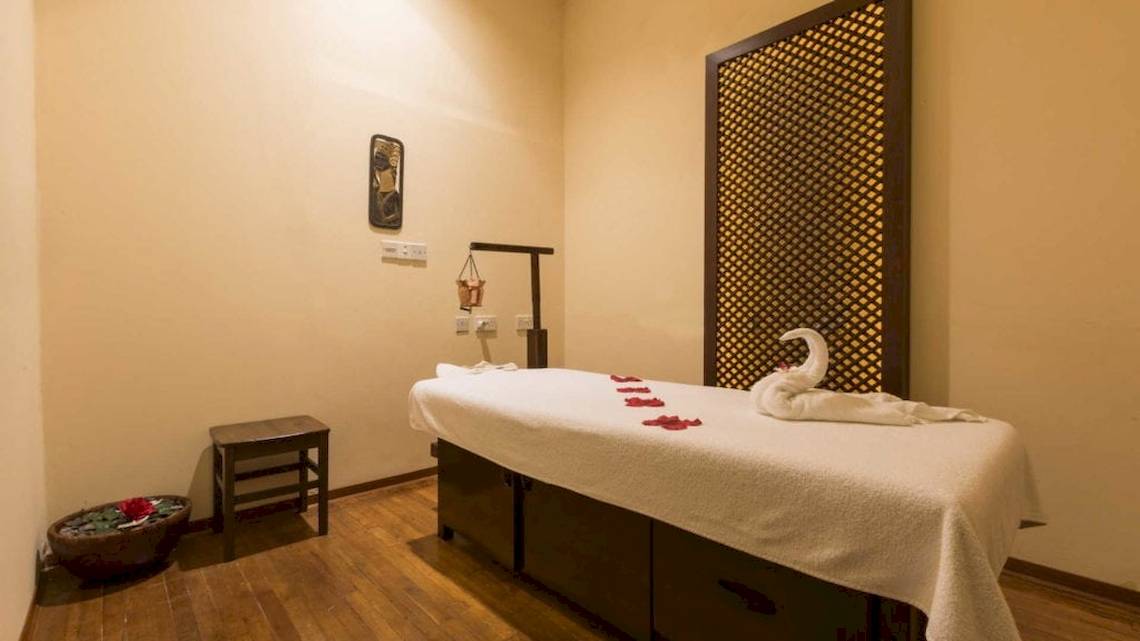 Massageraum im Seashells Resort at Suncrest mit einem Behandlungstisch, Rosenblättern und einem Tisch mit Blumen.
