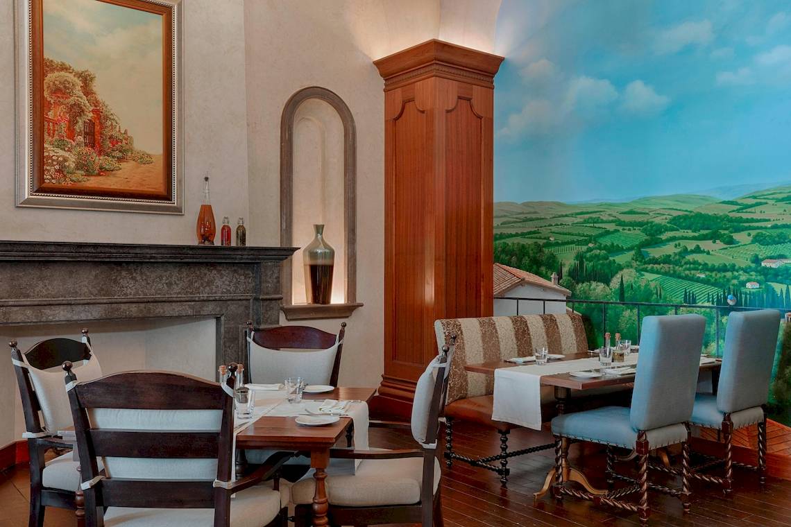 Speisesaal im St. Regis Abu Dhabi mit grüner Landschaft als Wandmalerei.