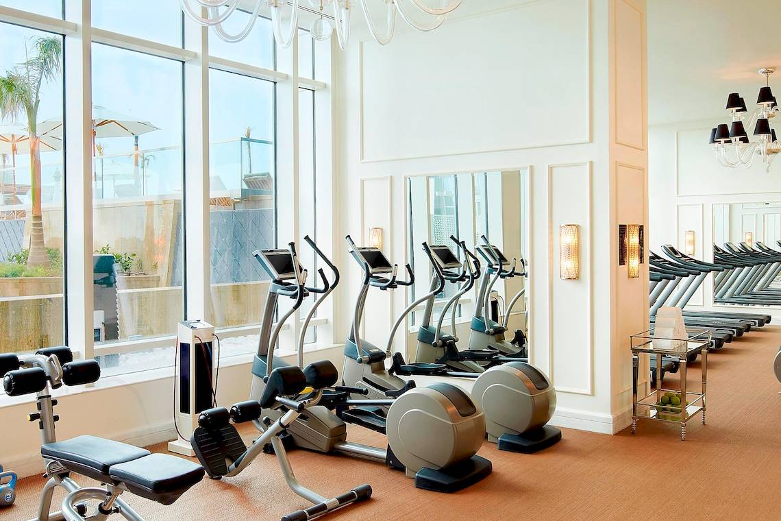 Fitnessstudio im St. Regis Abu Dhabi mit modernen Geräten und großen Fenstern.