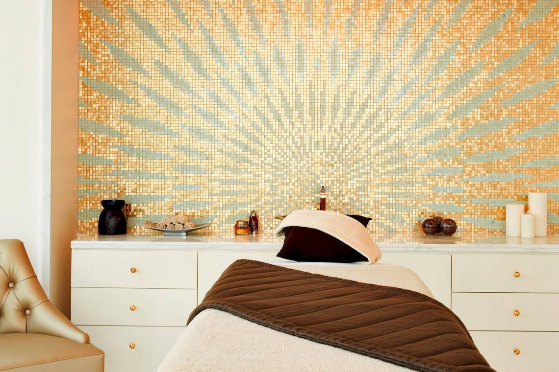 Wellnessbereich im St. Regis Abu Dhabi mit goldener Mosaikwand und Massageliege
