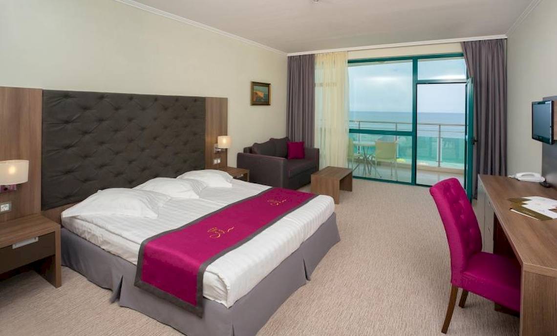 Hotelzimmer im Marina Grand Beach Hotel mit Meerblick, Bett, Schreibtisch und Sofa.