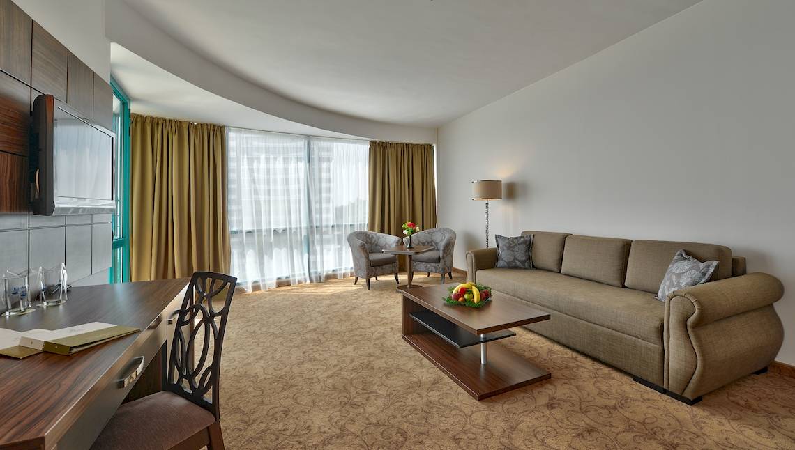Hotelwohnbereich mit Sofa, Tisch, Stühlen und Fernseher.