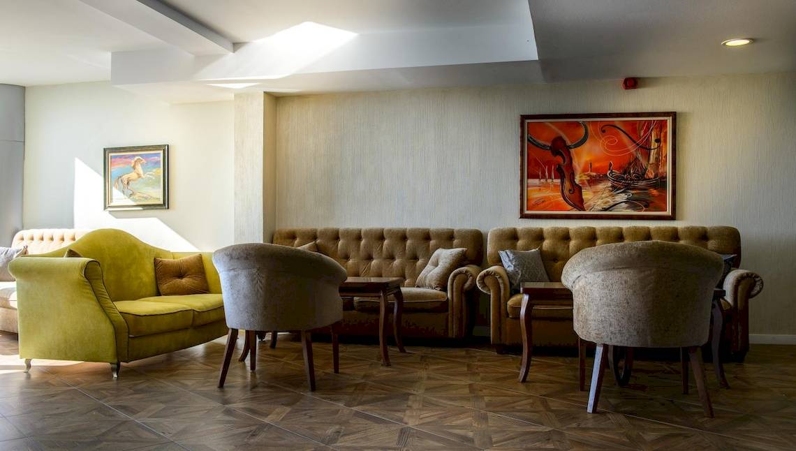 Lobby-Lounge im Marina Grand Beach Hotel mit Sofas, Sesseln und Gemälden an der Wand.