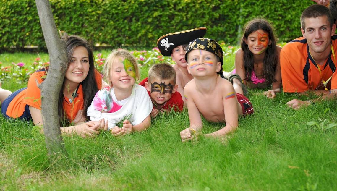 Gruppe von Kindern im Garten mit Gesichtsbemalung und Piratenkostümen, die auf dem Rasen liegen.
