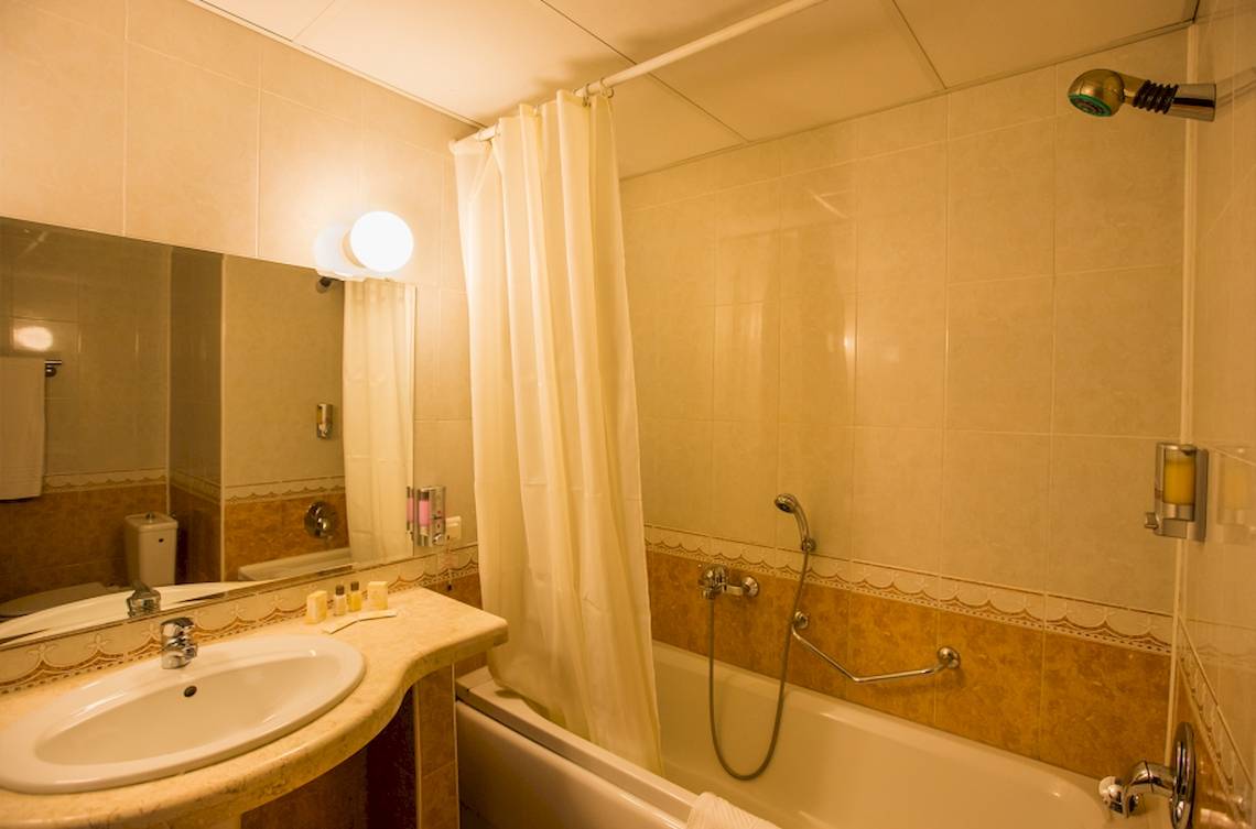 Badezimmer im Marina Grand Beach Hotel mit Badewanne, Spiegel und Waschbecken.