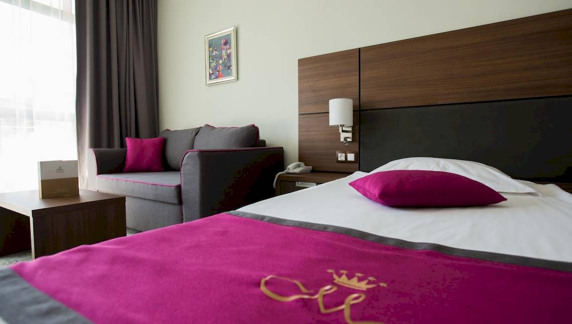 Hotelzimmer im Marina Grand Beach Hotel mit Bett, Sofa, Nachttisch und Fenster.