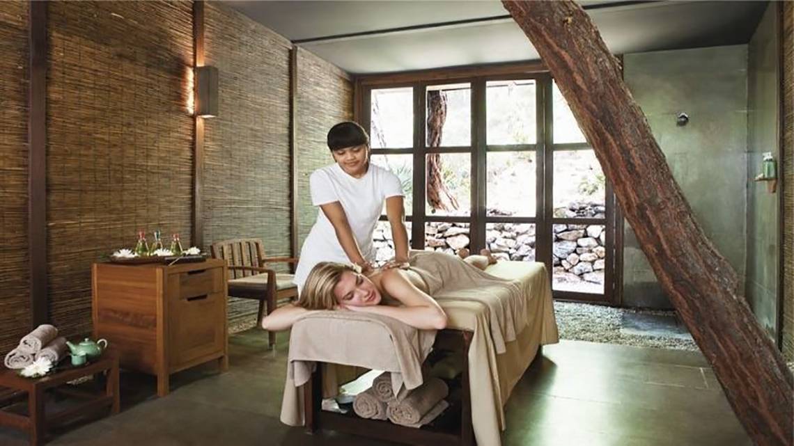 Eine Frau liegt entspannt auf einer Massageliege im Hillside Beach Club und wird von einer Therapeutin massiert.