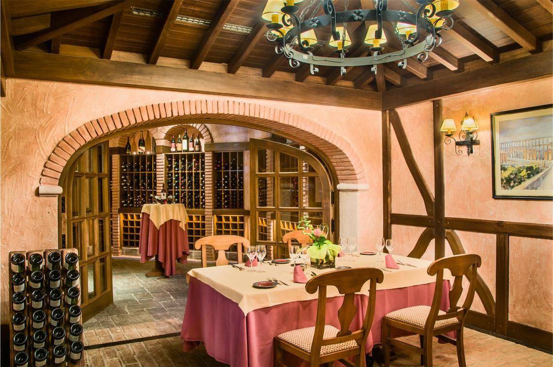 Ein elegantes Restaurant im Tivoli La Caleta Tenerife Resort mit einem Tisch, der mit Gläsern und einer Tischdecke serviert ist, in einem beleuchteten Weinkeller.