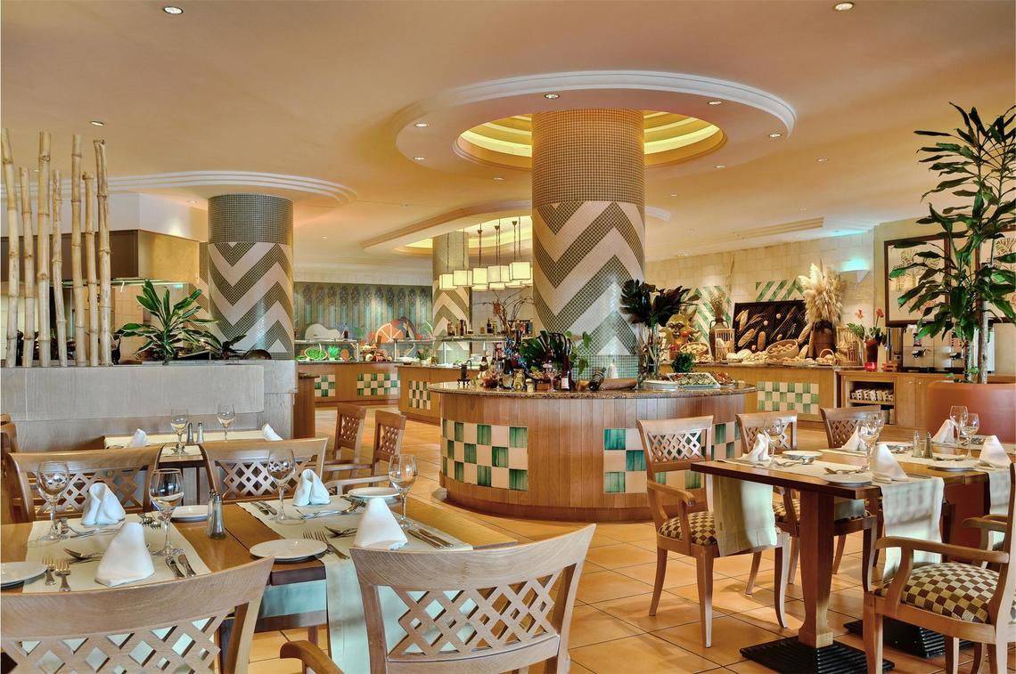 Ein Restaurantbereich im Tivoli La Caleta Tenerife Resort mit Tisch und Stühlen.